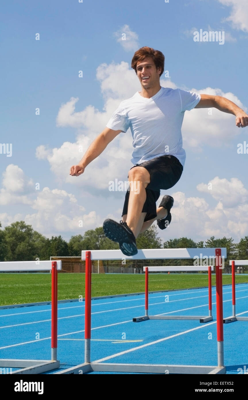Man jumping hurdles on a track Stock Photo Alamy