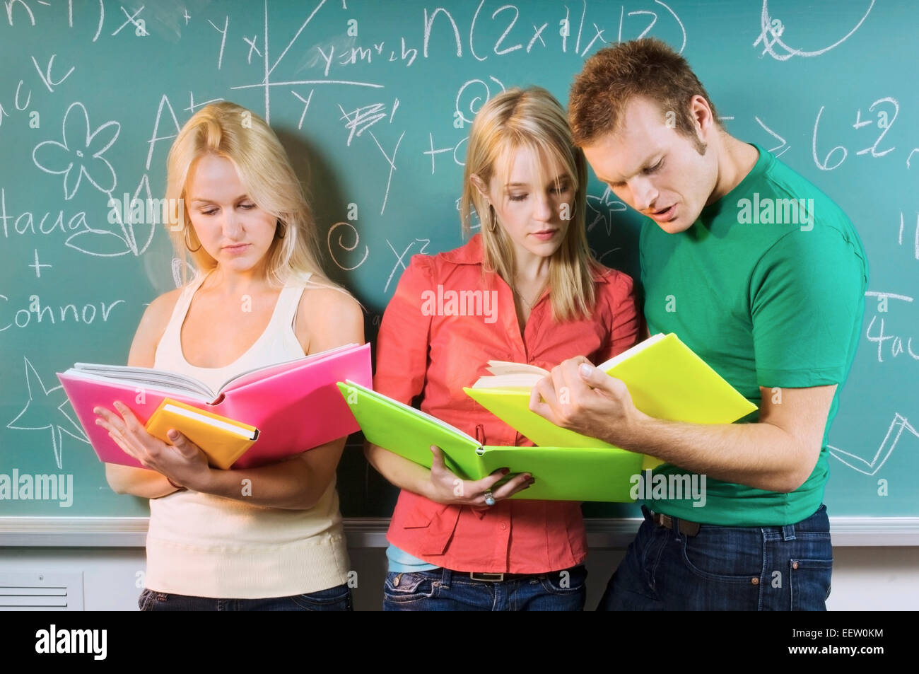 Three college students by a chalkboard Stock Photo