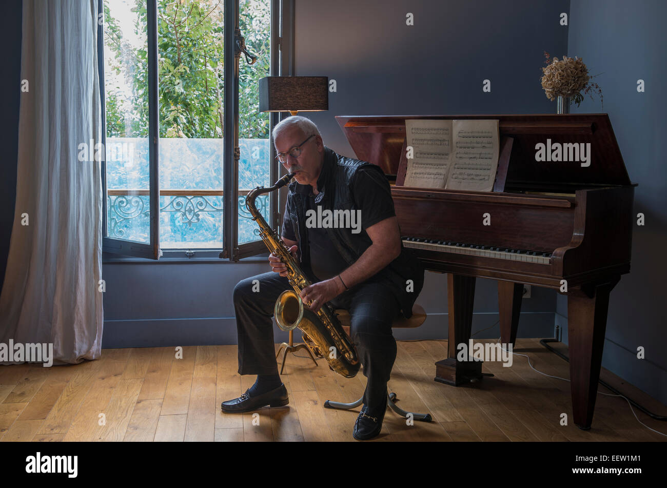 Mature male playing a saxophone in a music room Stock Photo