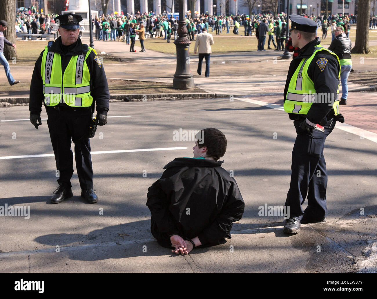 New Haven CT USA--  New Haven police talk to an intoxicated man that they have in handcuffs along Temple Street during the parade. Stock Photo