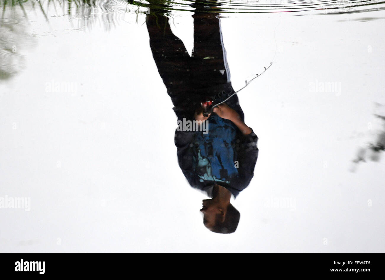 North Haven CT USA--  Corey Walters, 10, is seen reflected in the water as he fishes at the 19th Annual North Haven Fishing Derby, held at Sinoway Pond. He is from North Haven. Stock Photo