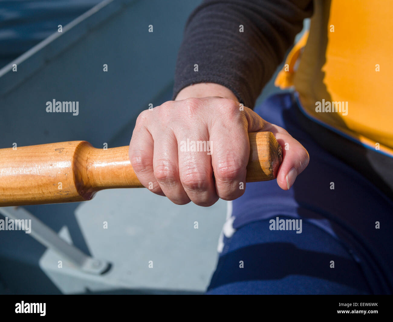 Hand holding an Oar and Rowing. A woman's hand on an boat's oar, rowing