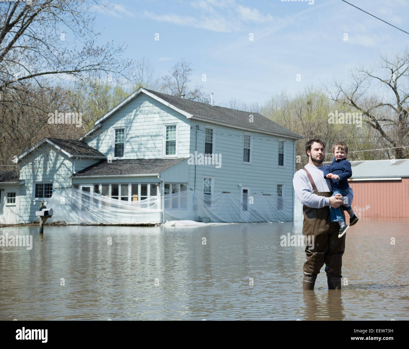 Father holding son standing in flooded street Stock Photo
