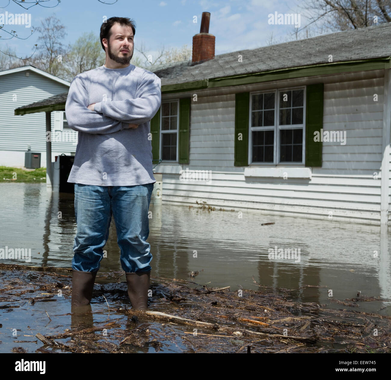 Man standing in front of flooded house Stock Photo