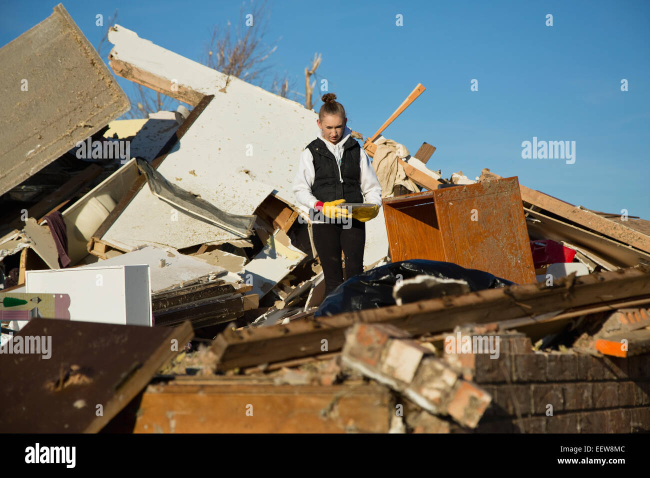 Woman on pile of rubble of house destroyed by tornado Stock Photo