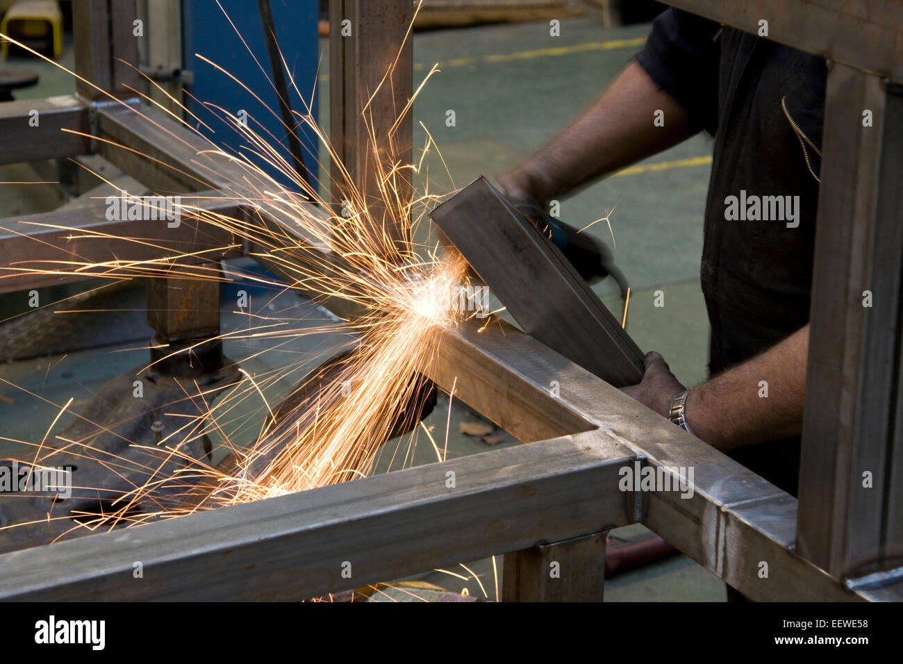 Metal fabricator grinding steel before welding making showers of sparks Stock Photo