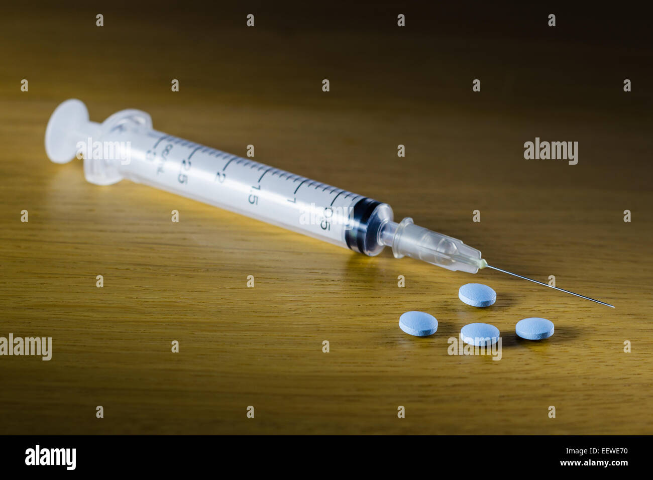 Drug syringe and cooked heroin on wood table Stock Photo