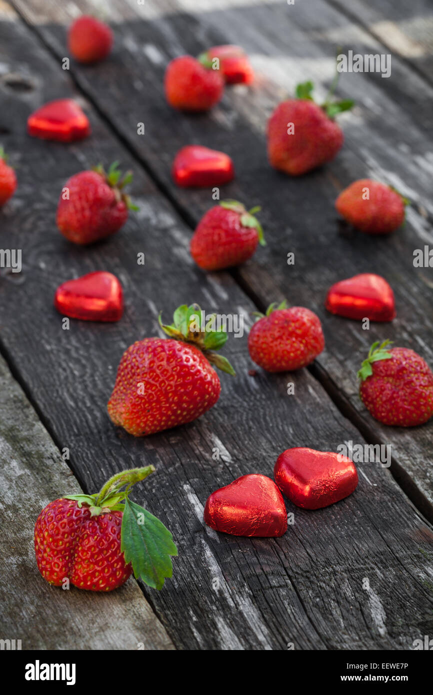 Fresh red strawberries and chocolate heart candy on old wooden table ...