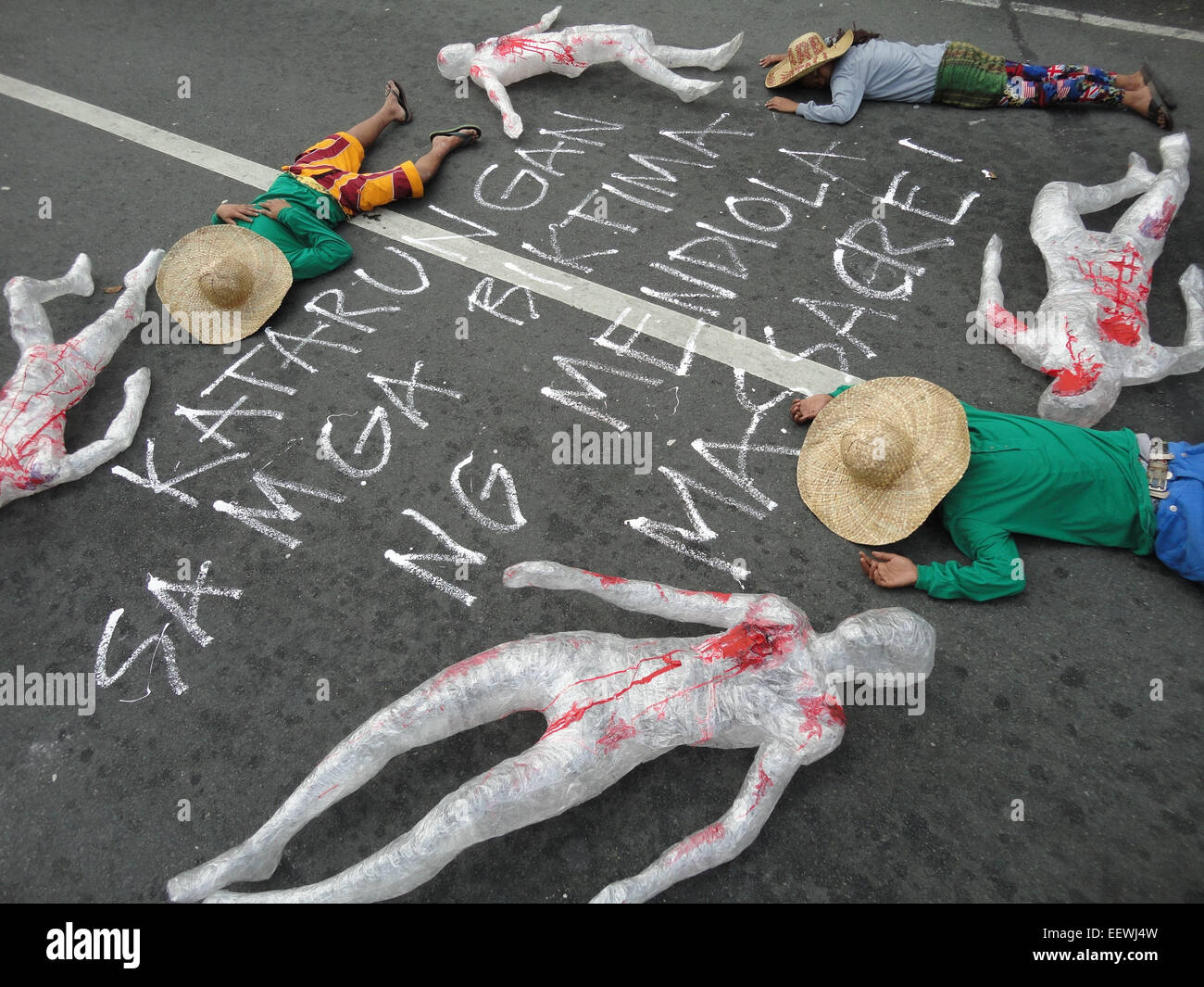 Filipino protesters, along with 'wounded' dummies, lie around a painted message that reads, 'Justice for the victims of Mendiola Massacre!' at Mendiola bridge, as they commemorate the 28th anniversary of the Mendiola Massacre that occured under the administration of President Benigno Aquino III's mother, former President Corazon Aquino, where thirteen farmers were killed. Anakpawis Partylist representative Fernando Hicap has filed a bill at Congress proposing to declare January 22, the anniversary of the Mendiola Massacre, a special holiday called 'Farmer's Day.' (Photo by Richard James Mendoz Stock Photo