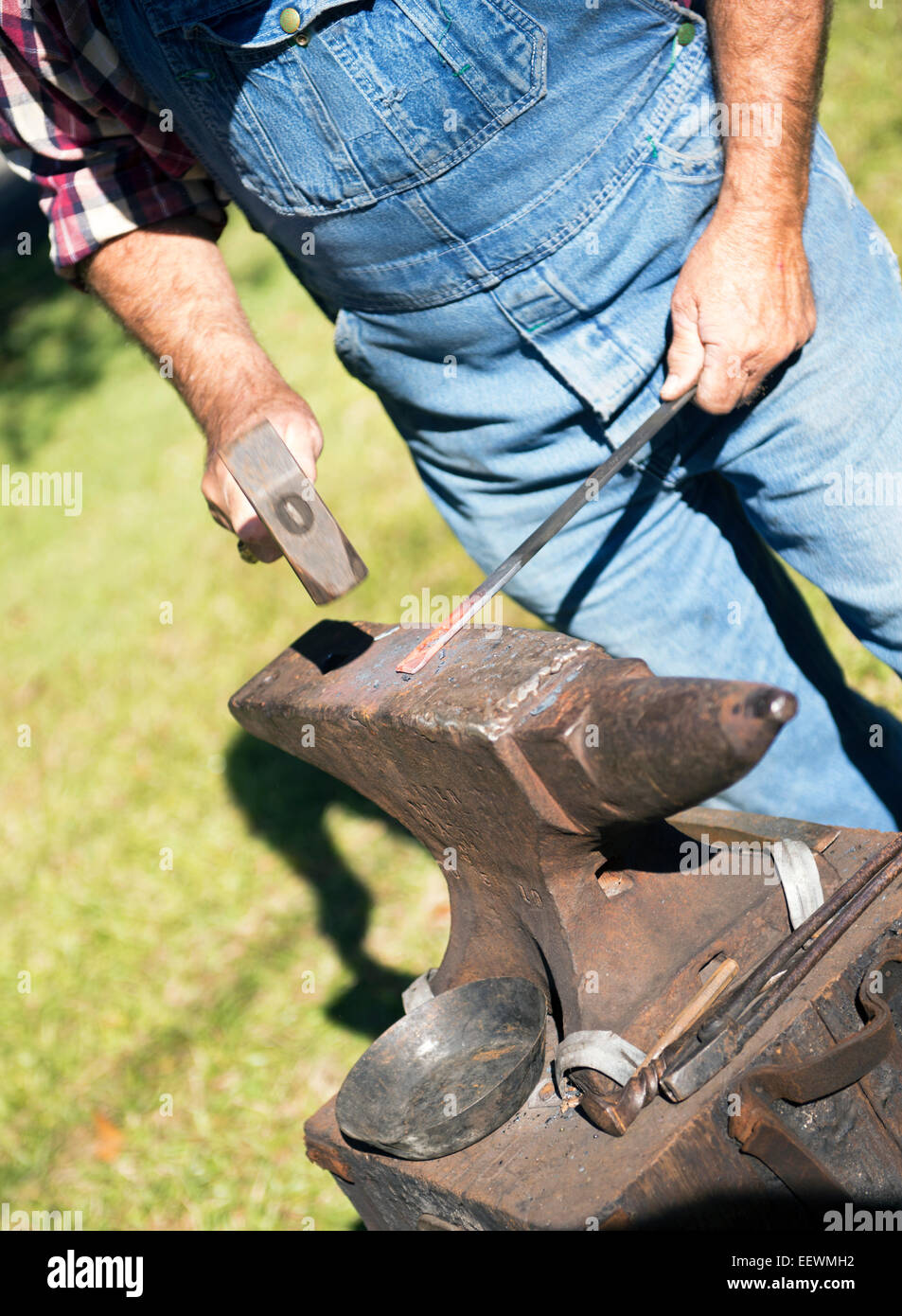 Blacksmith pounding steel on an anvil outdoors -  off center Stock Photo