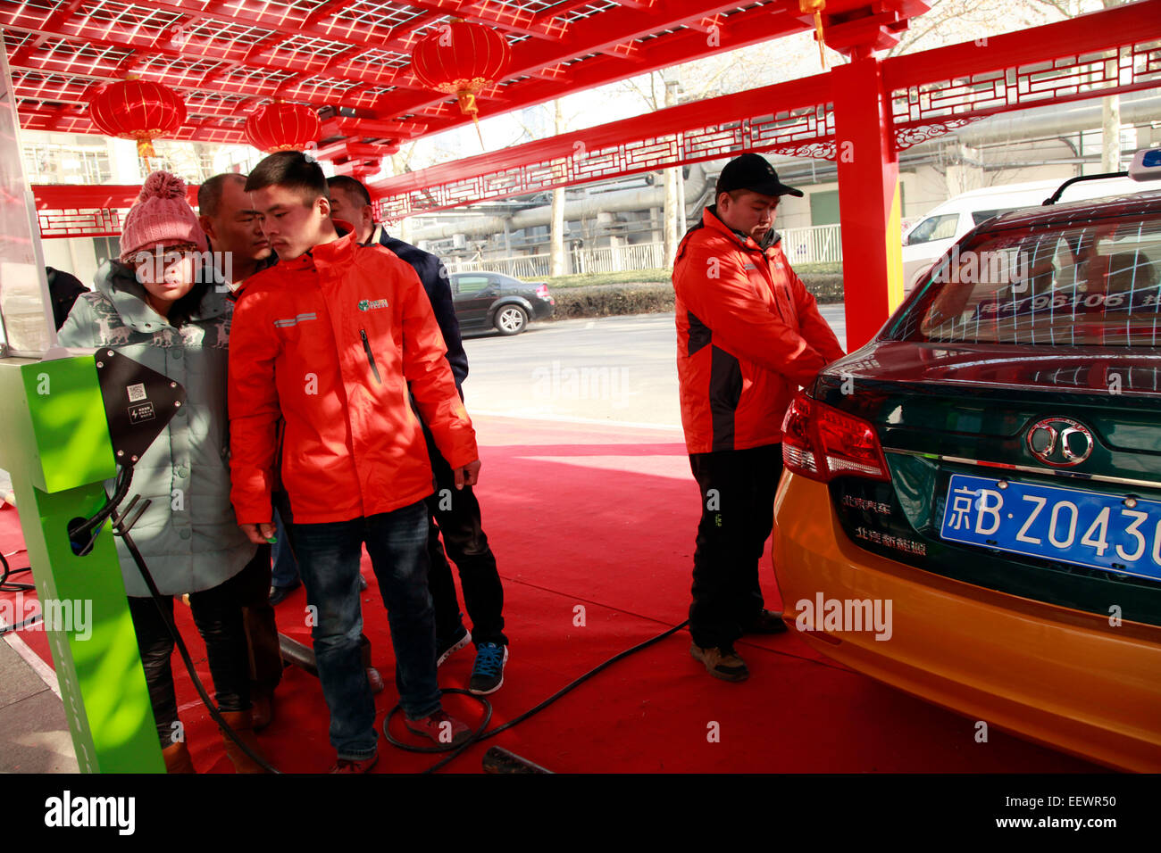 Beijing, China. 22nd Jan, 2015. A staff (R) recharges an electric taxi at a new photovoltaic power station in Beijing, capital of China, Jan. 22, 2015. Beijing's first photovoltaic power station for electric vehicles has been launched recently in the city's central business district (CBD). In 2015, Beijing plans to add 100 more photovoltaic power stations with 3,500 charging units to cover the power needs of its electric vehicles. © Pan Xu/Xinhua/Alamy Live News Stock Photo