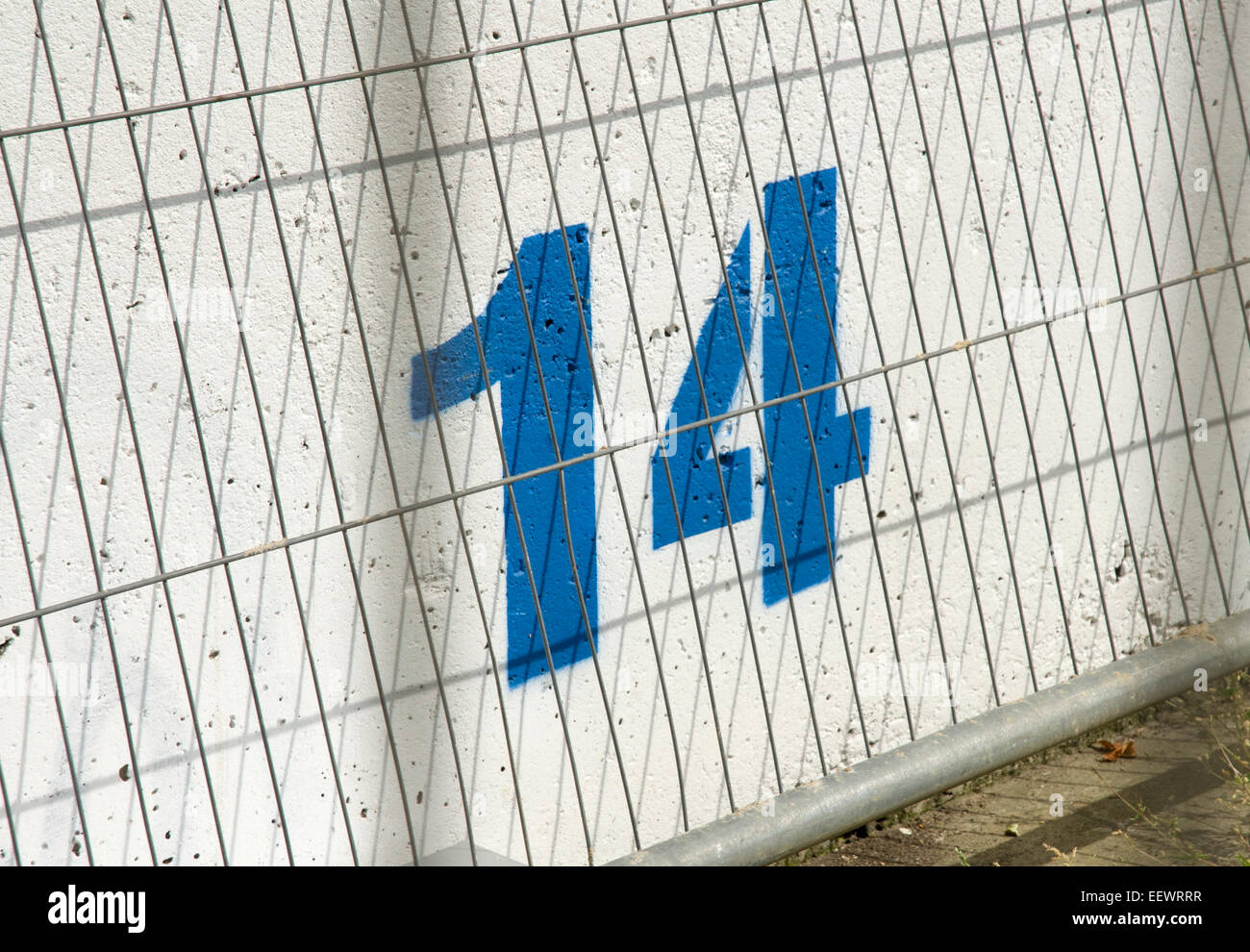 Number 14 fourteen painted in blue on a while concrete wall Stock Photo
