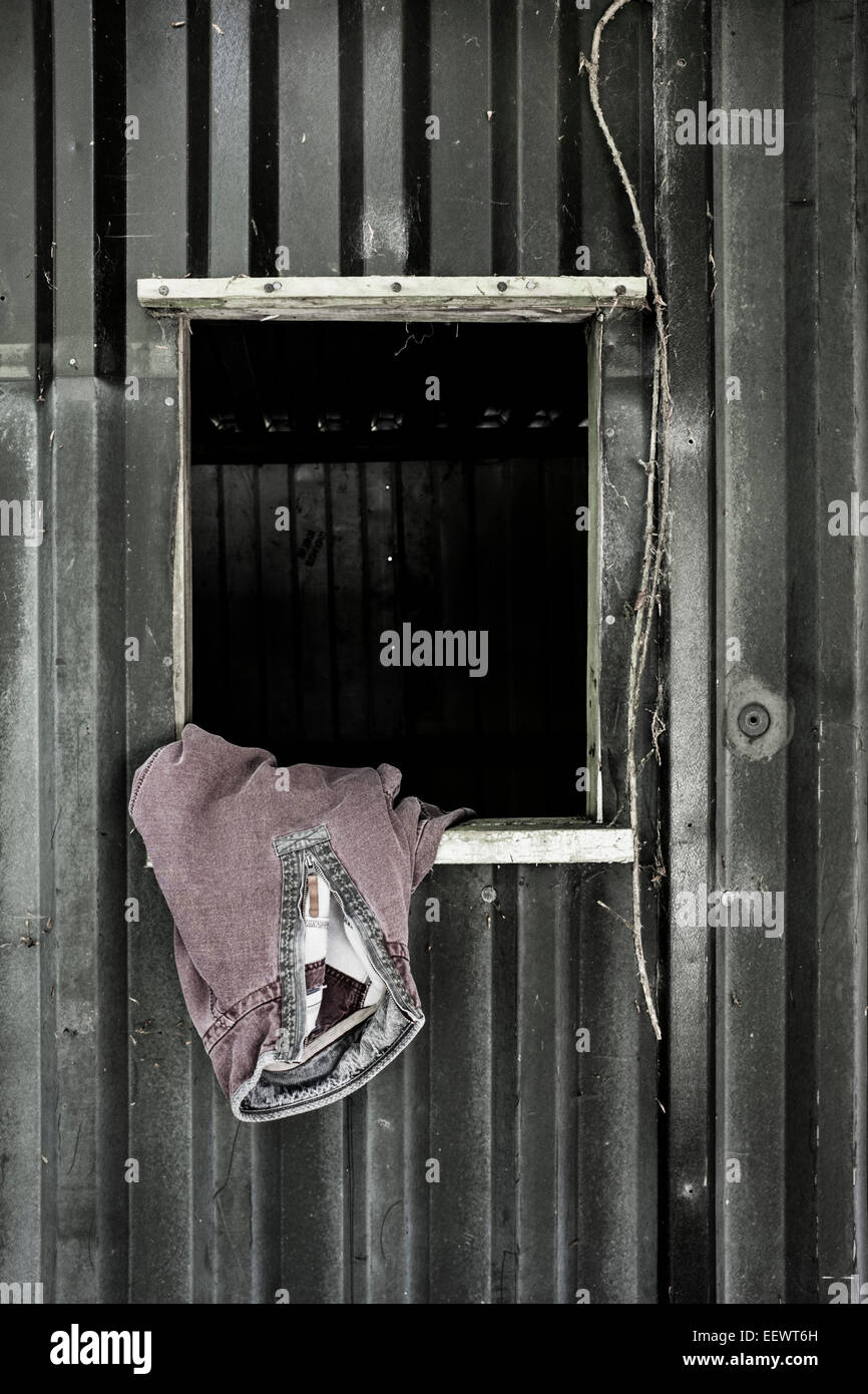 A man's sweatshirt hanging in th window of a farm building. Stock Photo