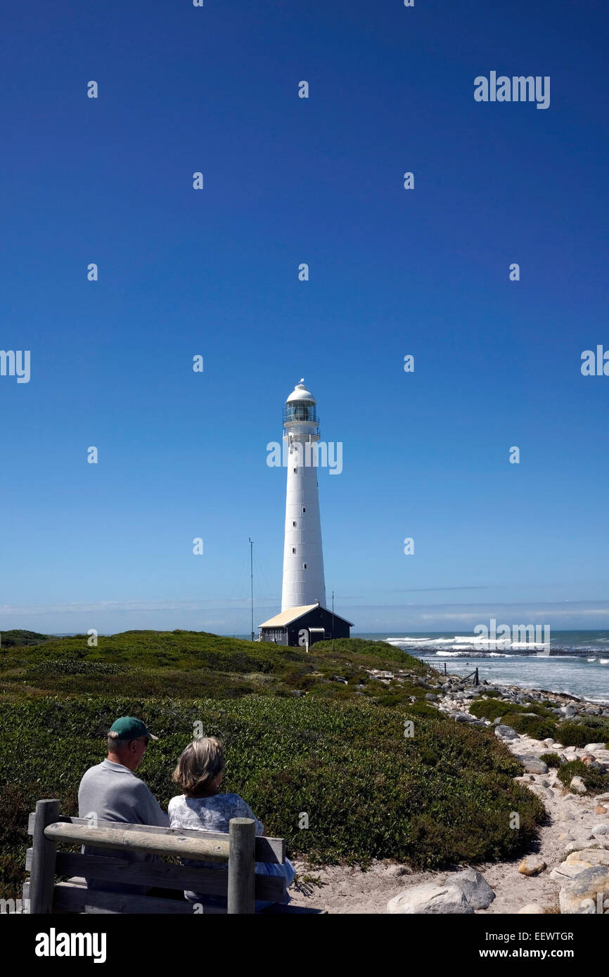 Couple sitting on a bench enjoying the view at the Slangkop Point lighthouse in Kommetjie, near Cape Town. Stock Photo
