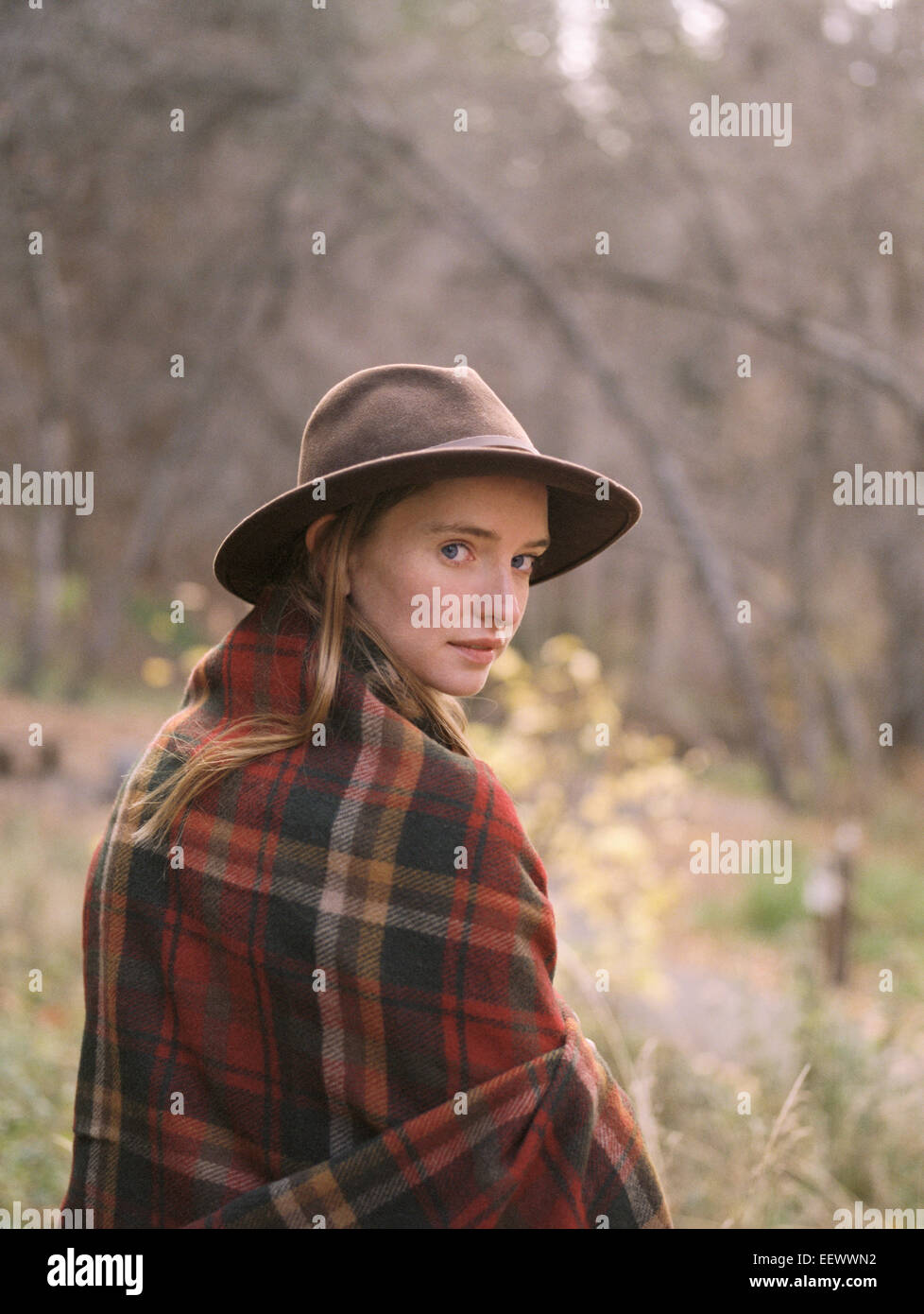 Young blond woman wearing a hat, wrapped in a blanket. Stock Photo