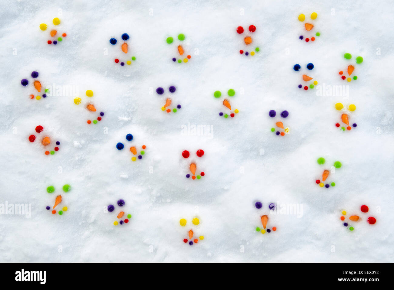 Smiling happy colourful snowman faces in the snow Stock Photo