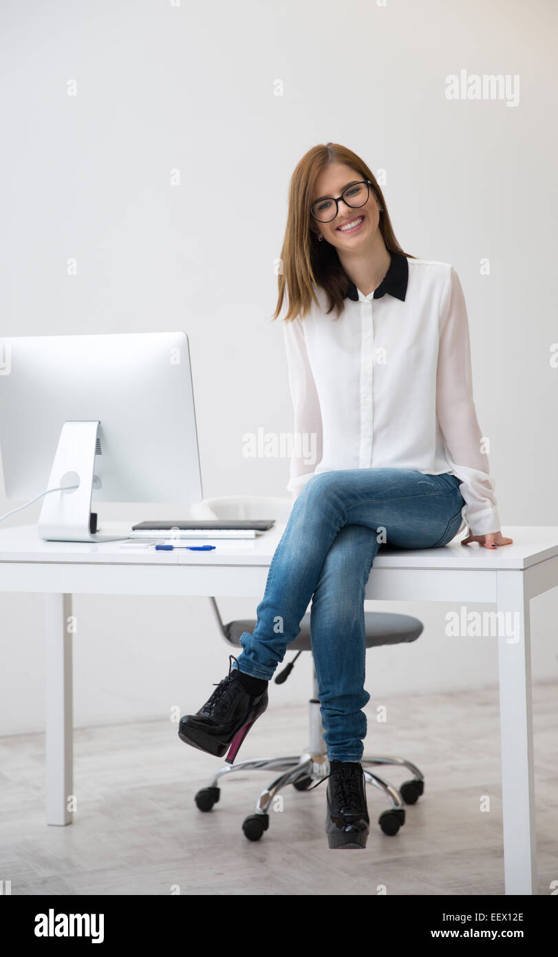 Portrait of attractive happy businesswoman sitting on the table Stock ...