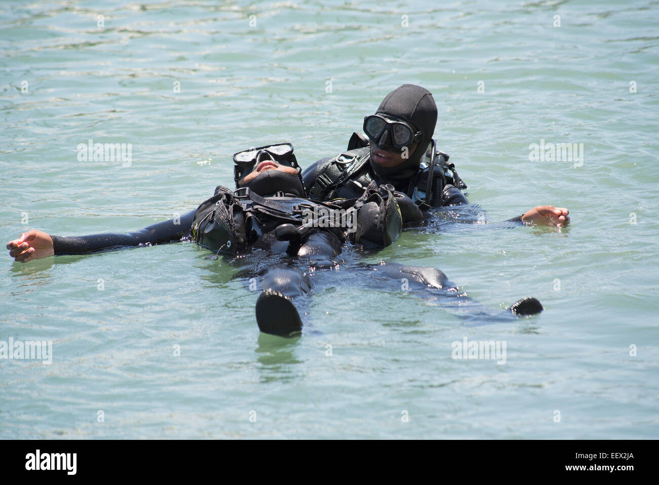 Commercial deep sea diver training simulating a rescue situation One diver rescues another Stock Photo