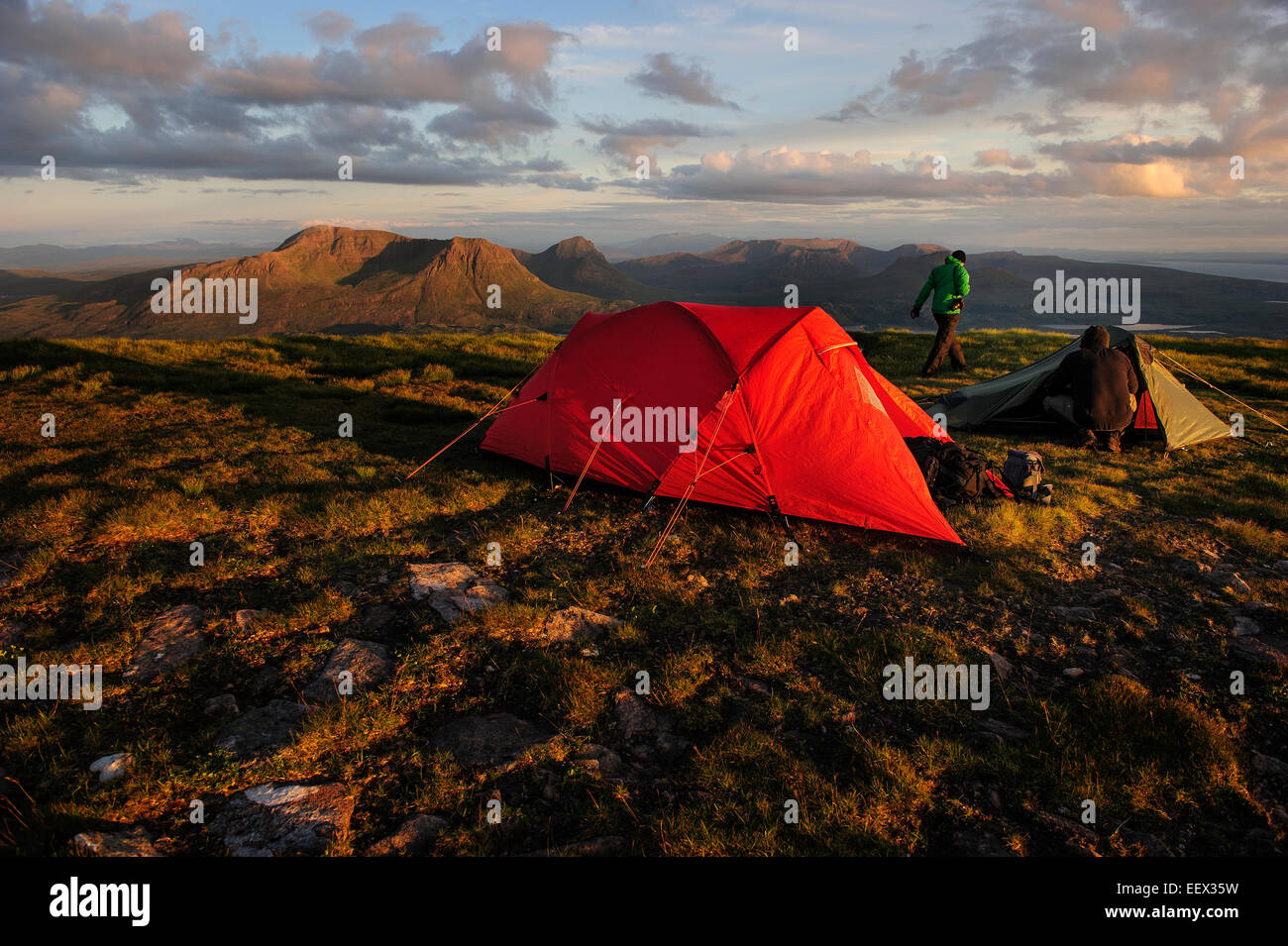 A hiker setting up camp at the Summit of a mountain. The Suilven, Scotland, United Kingdom. Stock Photo