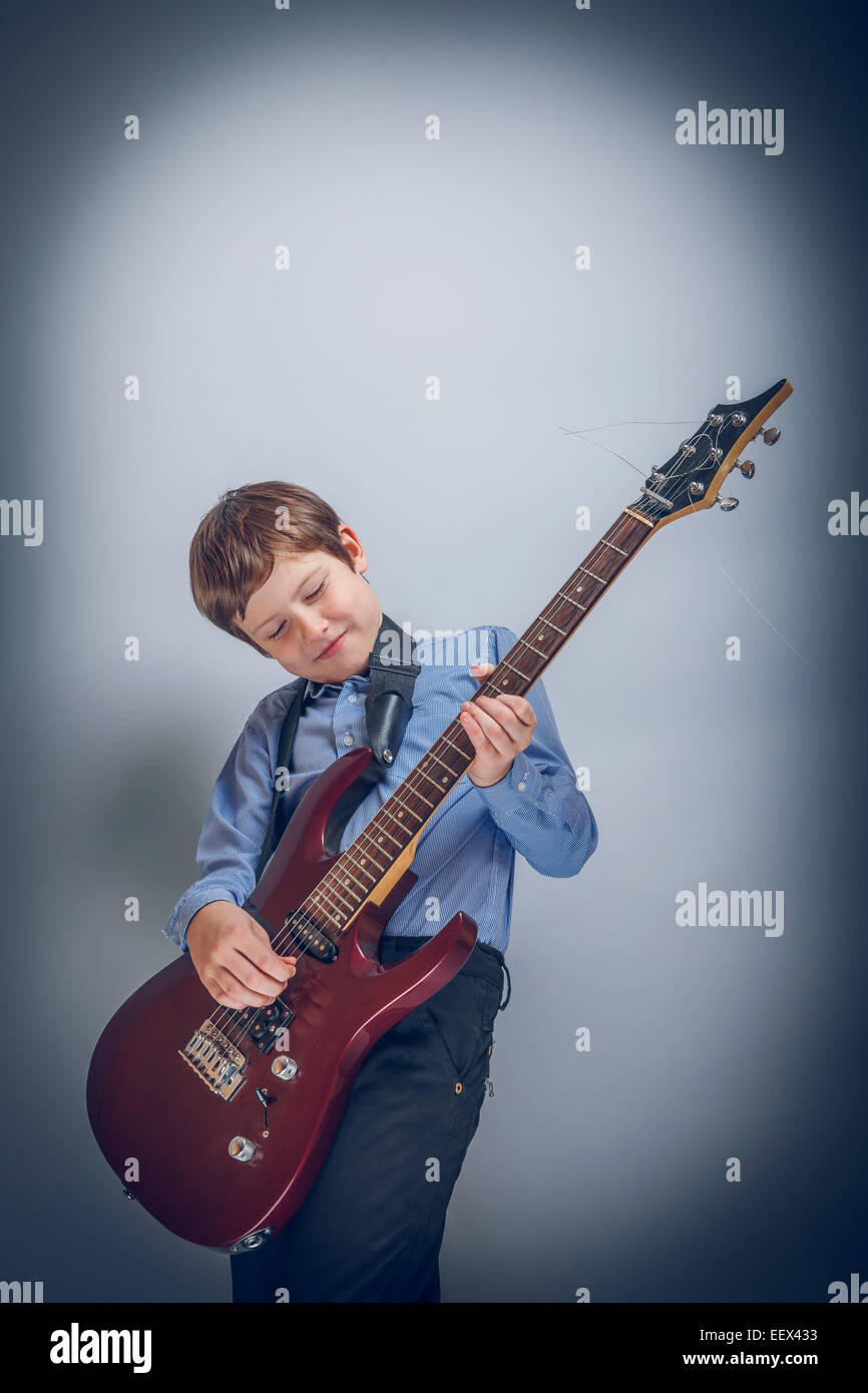 Teen boy playing  guitar on gray  background cross process Stock Photo