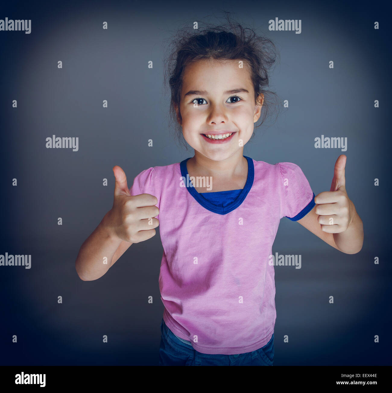 Teen girl shows gesture yes on gray background cross process Stock Photo