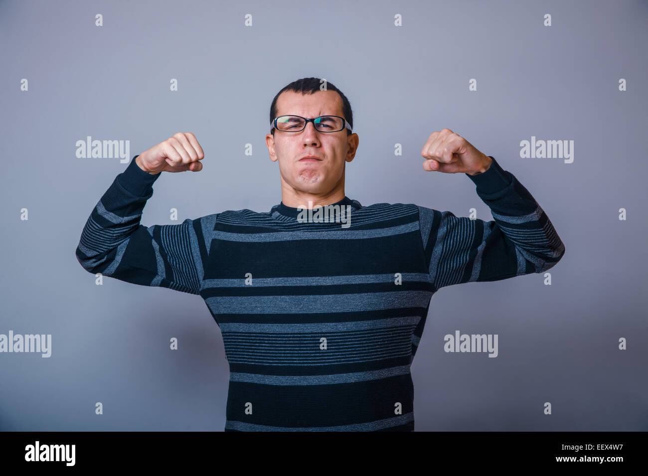 European-looking man years in glasses shows muscles Stock Photo