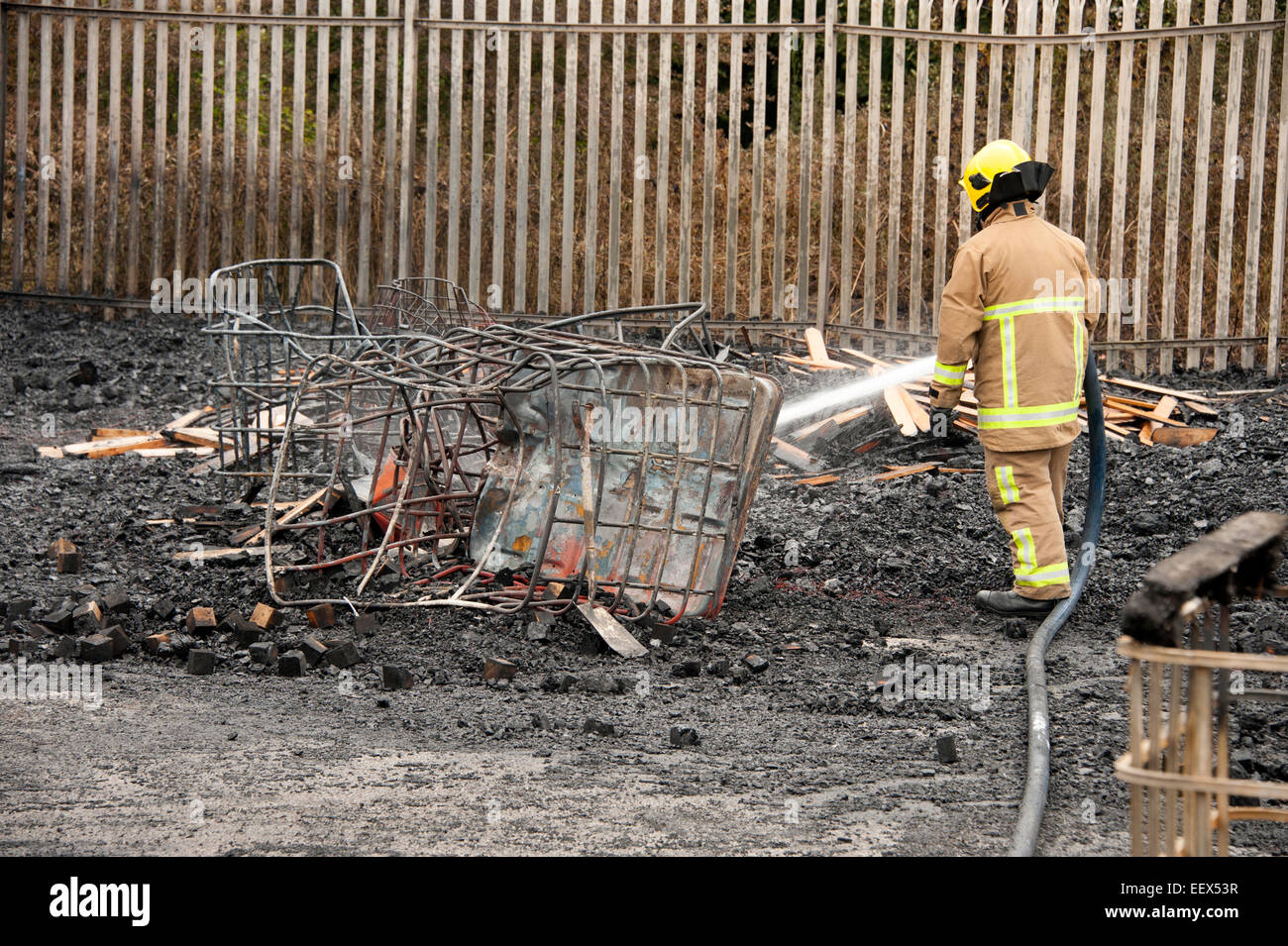 Fireman damping down embers burnt fire arson Stock Photo