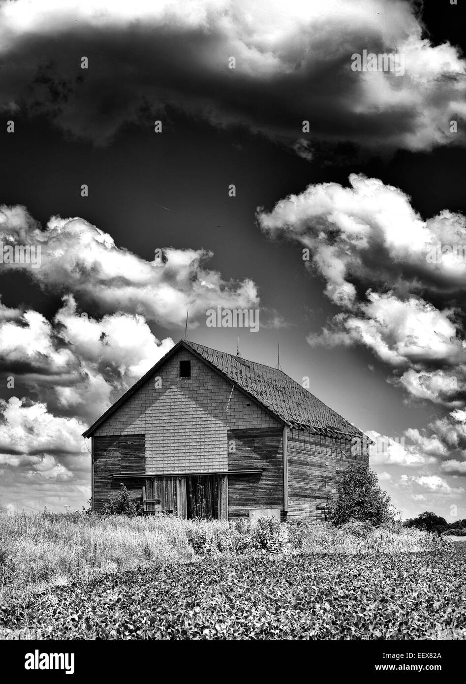 Spooky old desolate haunted barn with storm clouds overhead like you would see on Halloween in Black and White Stock Photo