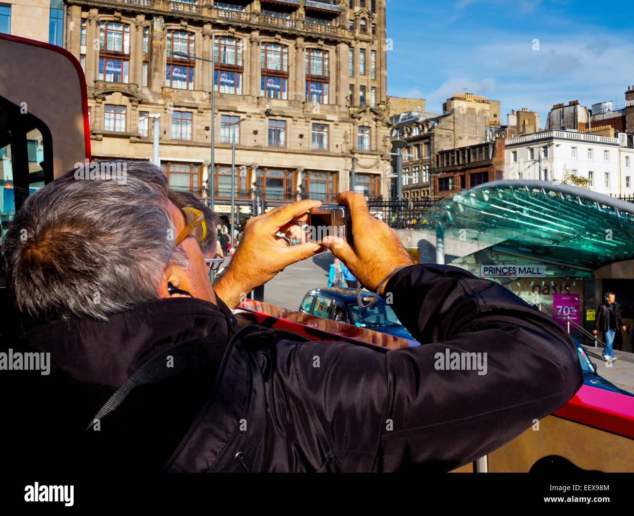 View of tourist on open top bus taking photographs on tour of Edinburgh city centre Scotland UK Stock Photo