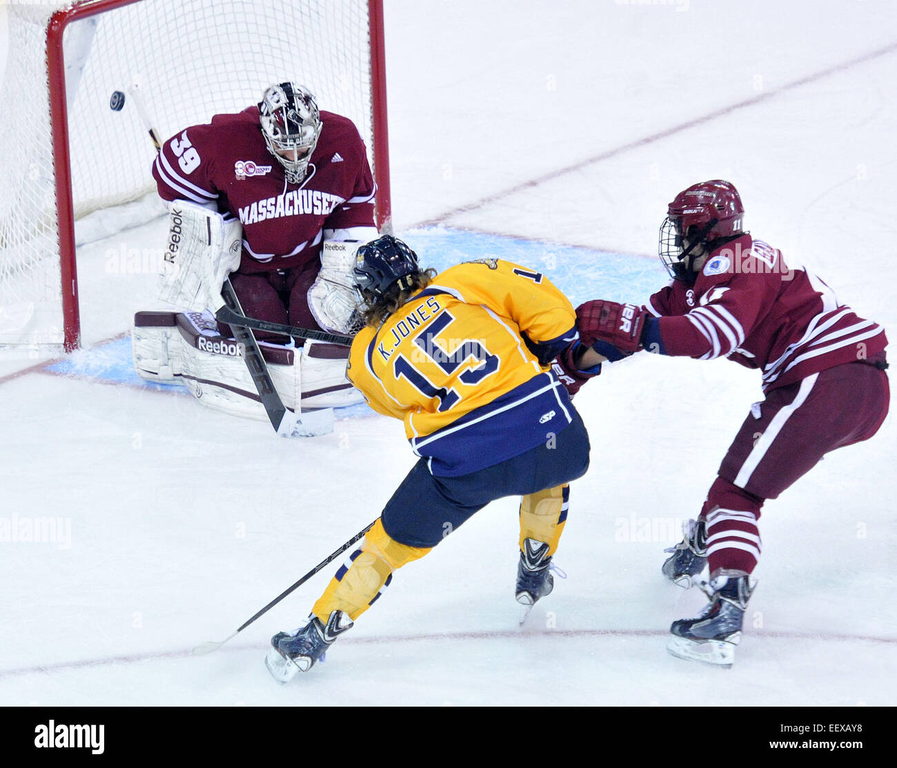 Quinnipiac's Kellen Jones puts the puck in the net past Umass' Steve Masalerrz during the first period. On the right for Providence is Ben Gallagher. Stock Photo