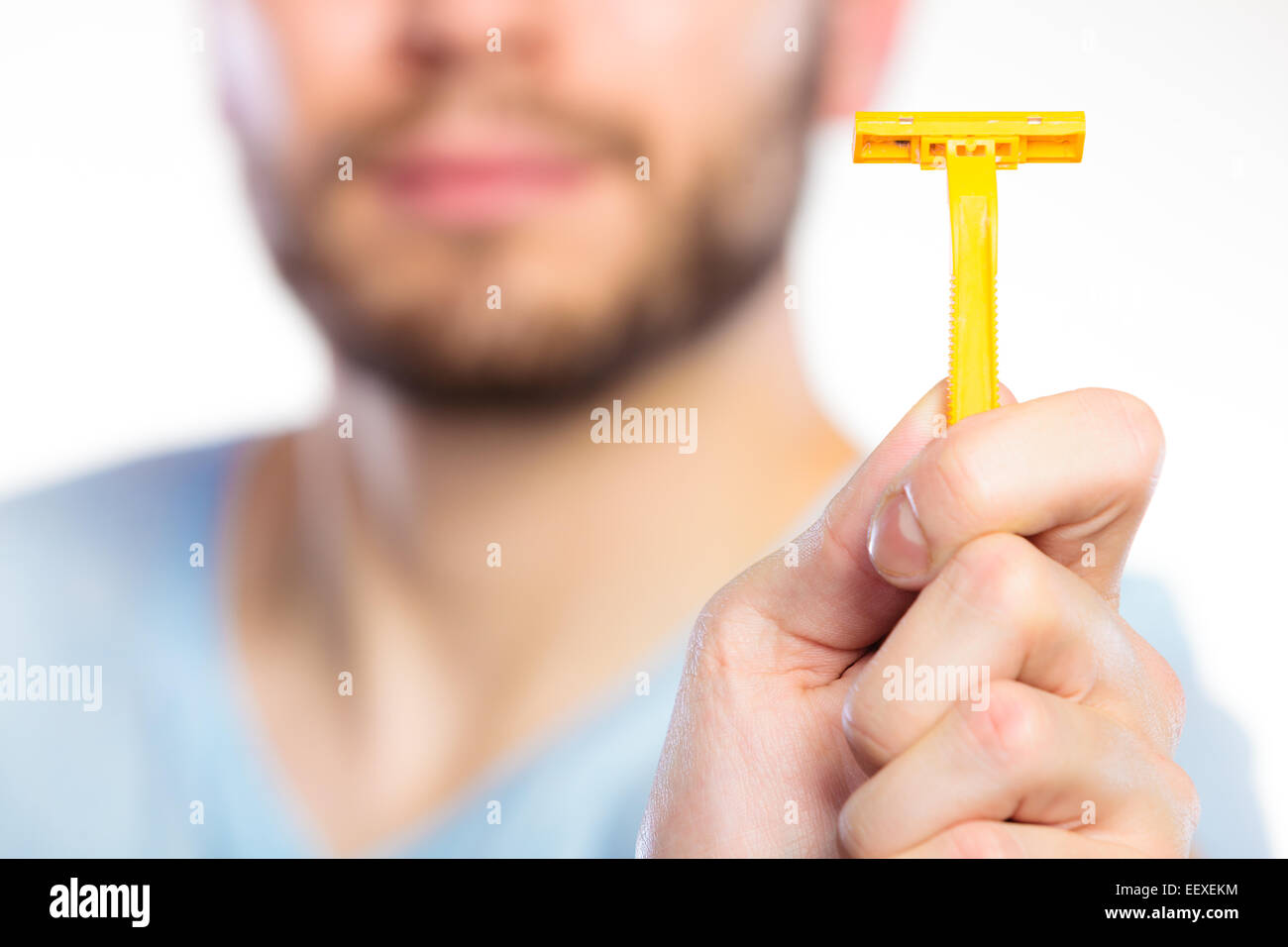 Young man guy with beard showing disposable yellow razor blade, studio ...