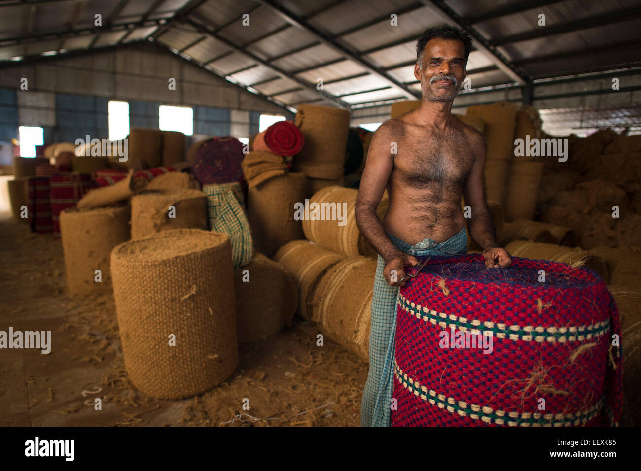 Worker with rolled coconut fibre mats or coir mats, coconut fibre industry, factory, Alappuzha, Kerala, India, Asia Stock Photo