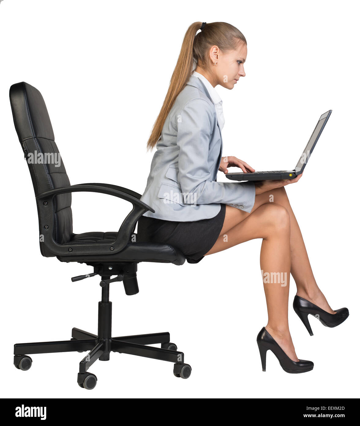 Businesswoman sitting on the edge of office chair, with laptop Stock Photo