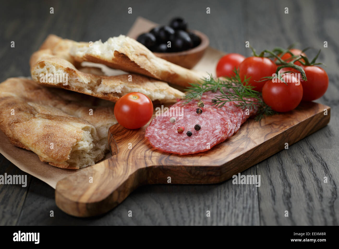 Antipasti with salami, olives, tomatoes and bread on wood table Stock Photo