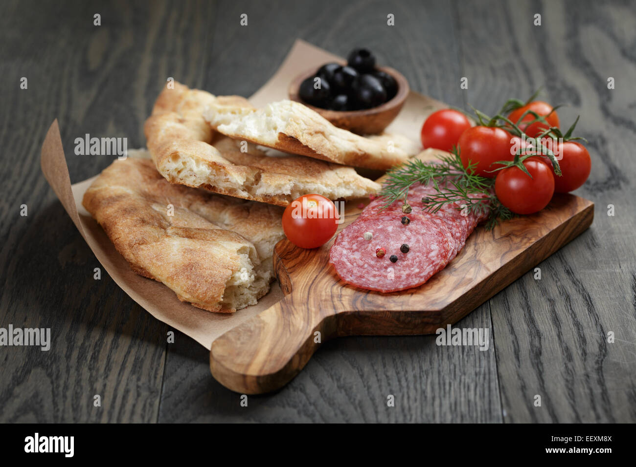 Antipasti with salami, olives, tomatoes and bread on wood table Stock Photo