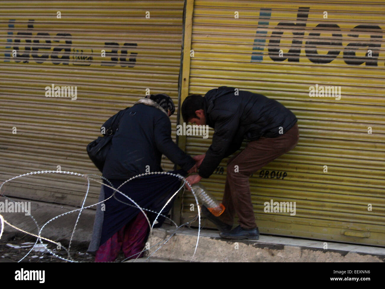 Srinagar, Indian Administered Kashmir:23January A kashmiri man helps a women near concentina razor wire during restrictions imposed by the authorities following the strike call given by Separtists against the publication of Blasphemous cartoon by Charlie Hebdo Magazine in Srinaga Credit: Sofi Suhail/Alamy Live News Stock Photo