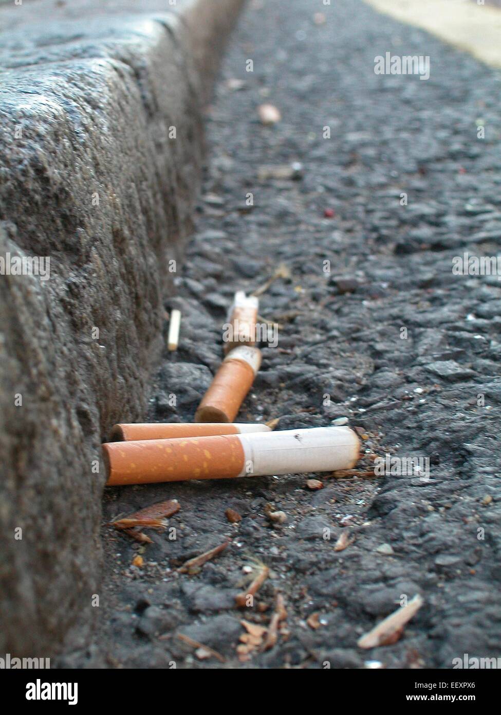 Cigarette Cigarettes butts in gutter discarded smoking material litter Health issues Stock Photo