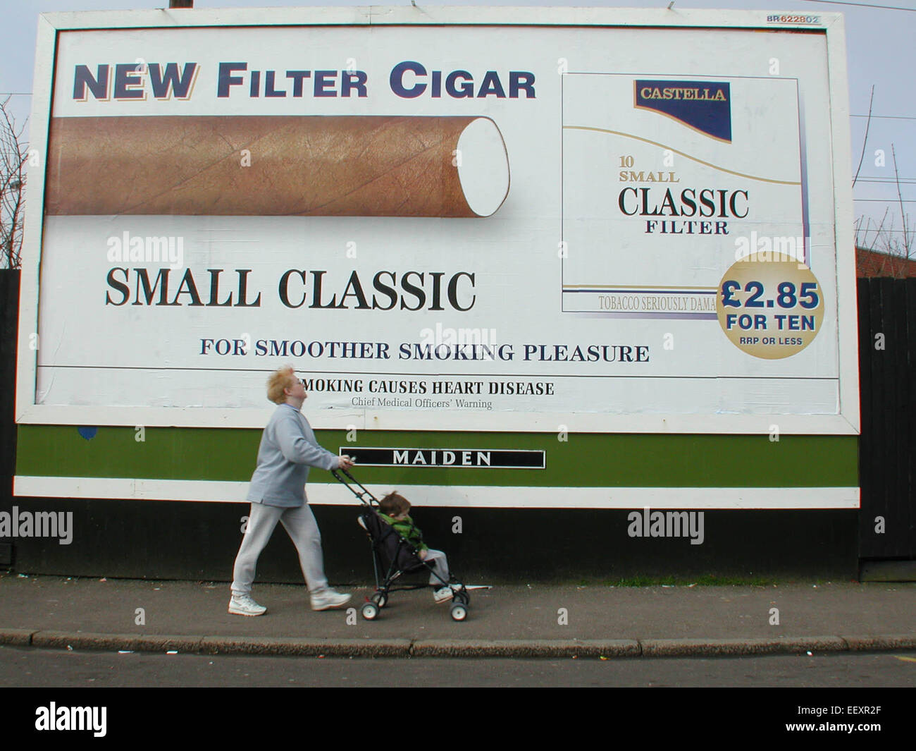 children and smoking Woman with child in pushchair passing Maiden poster hoarding advertising tobacco related products Stock Photo