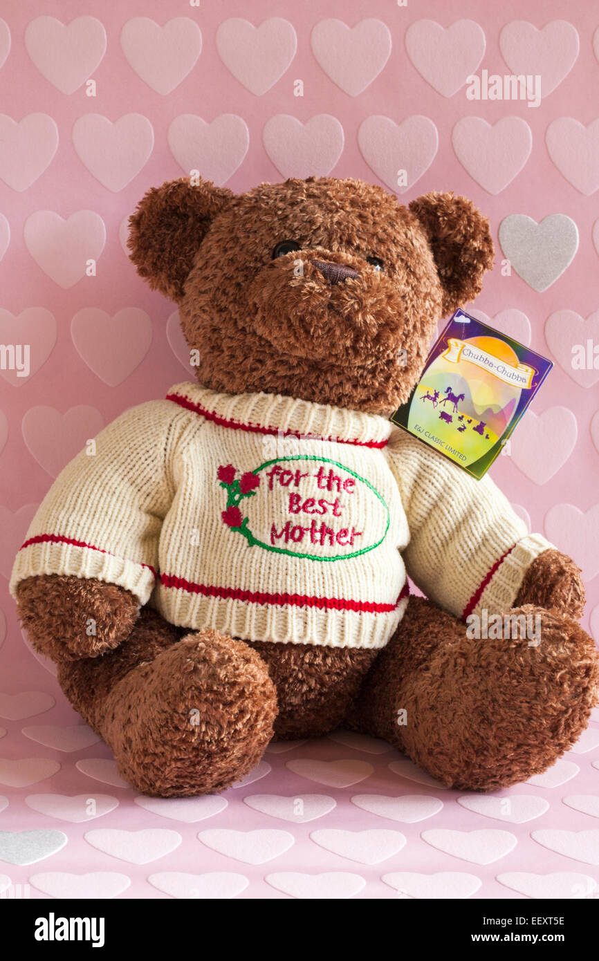 Teddy bear soft cuddly toy sat wearing for the best mother jumper set on pink hearts background - Mothers Day, Mothering Sunday gift present Stock Photo