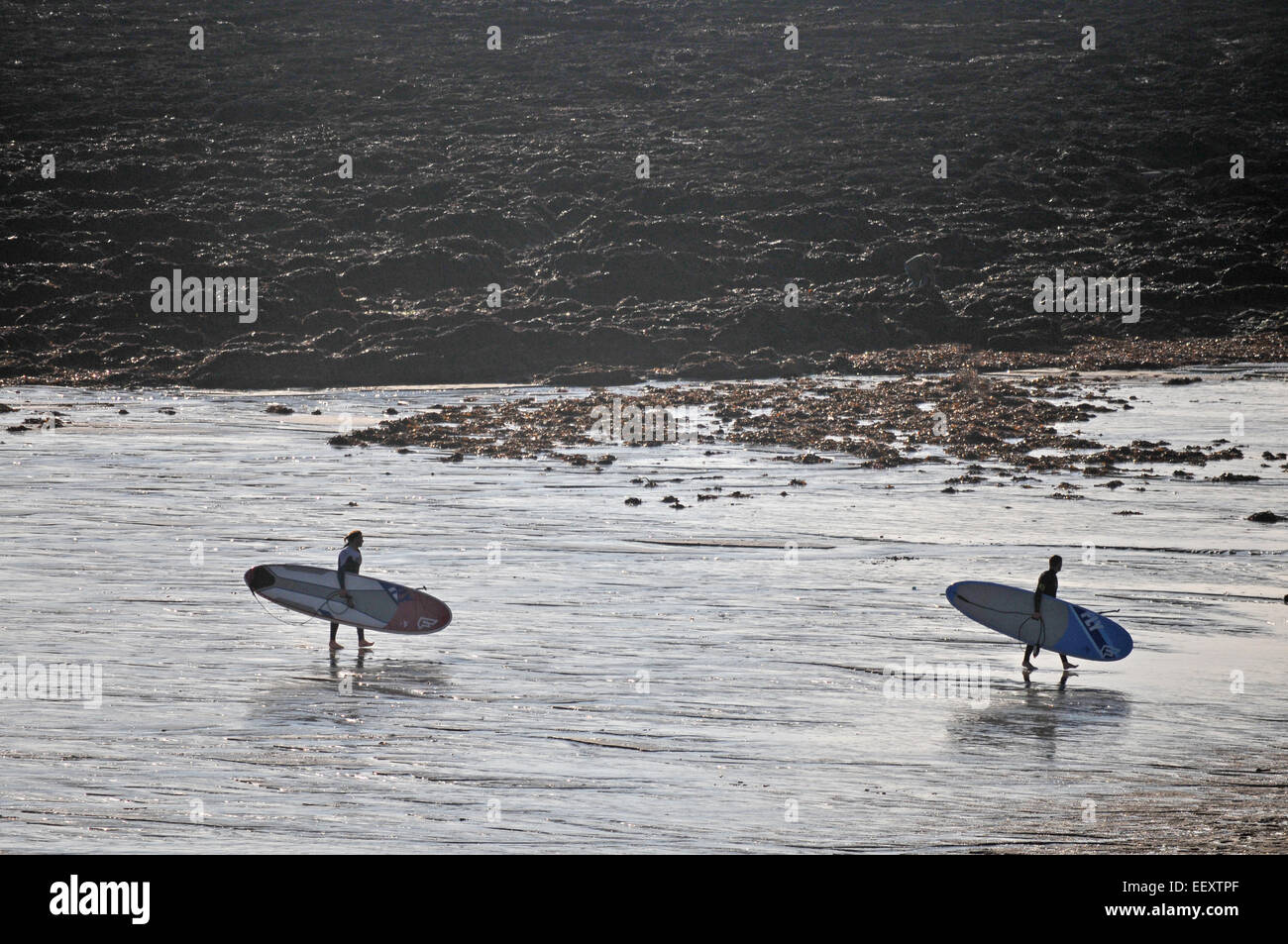 Two surfers in the early evening on Gyllyngvase Beach, Falmouth, UK Stock Photo