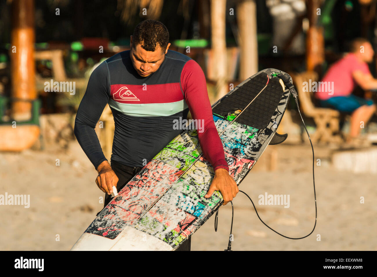 Surfer waxing his board at this popular south beach north of San Juan del Sur; Playa Maderas, San Juan del Sur, Rivas, Nicaragua Stock Photo