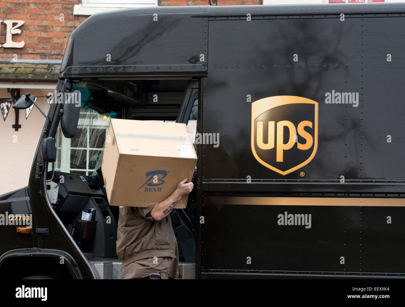 UPS Parcels Delivery Van With Driver Carrying A Large Parcel Stock 