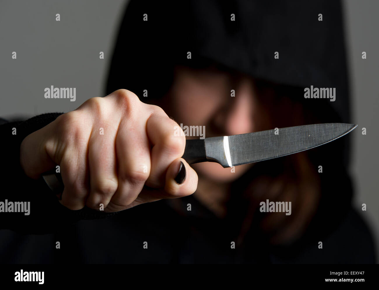 Female wearing a hooded top or 'hoodie' brandishing a knife symbolizing gang culture. Stock Photo