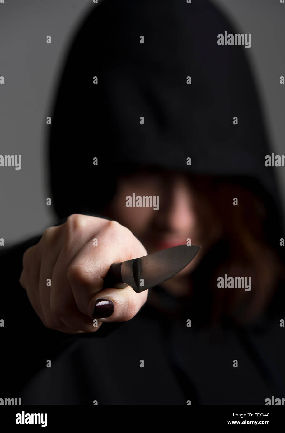 Female wearing a hooded top or 'hoodie' brandishing a knife symbolizing gang culture. Stock Photo