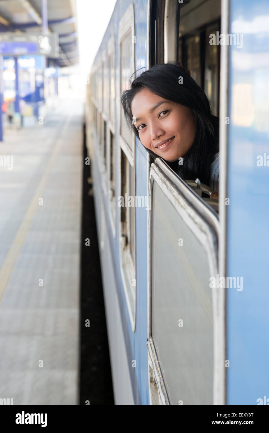 woman looking out the open window of the train at the railway station Stock Photo