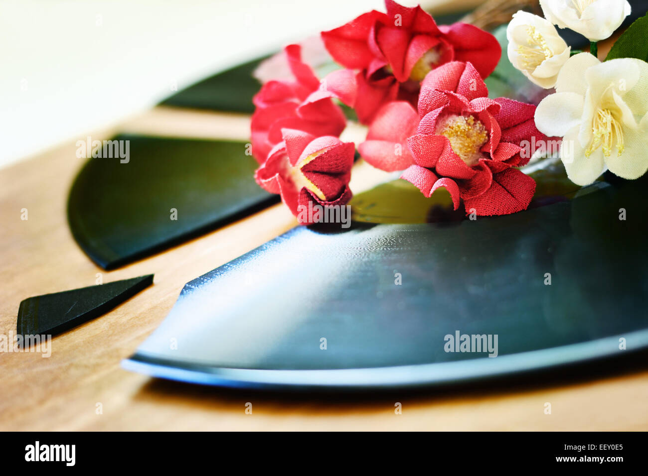 Red and white artificial flowers are on a broken gramophone record Stock Photo
