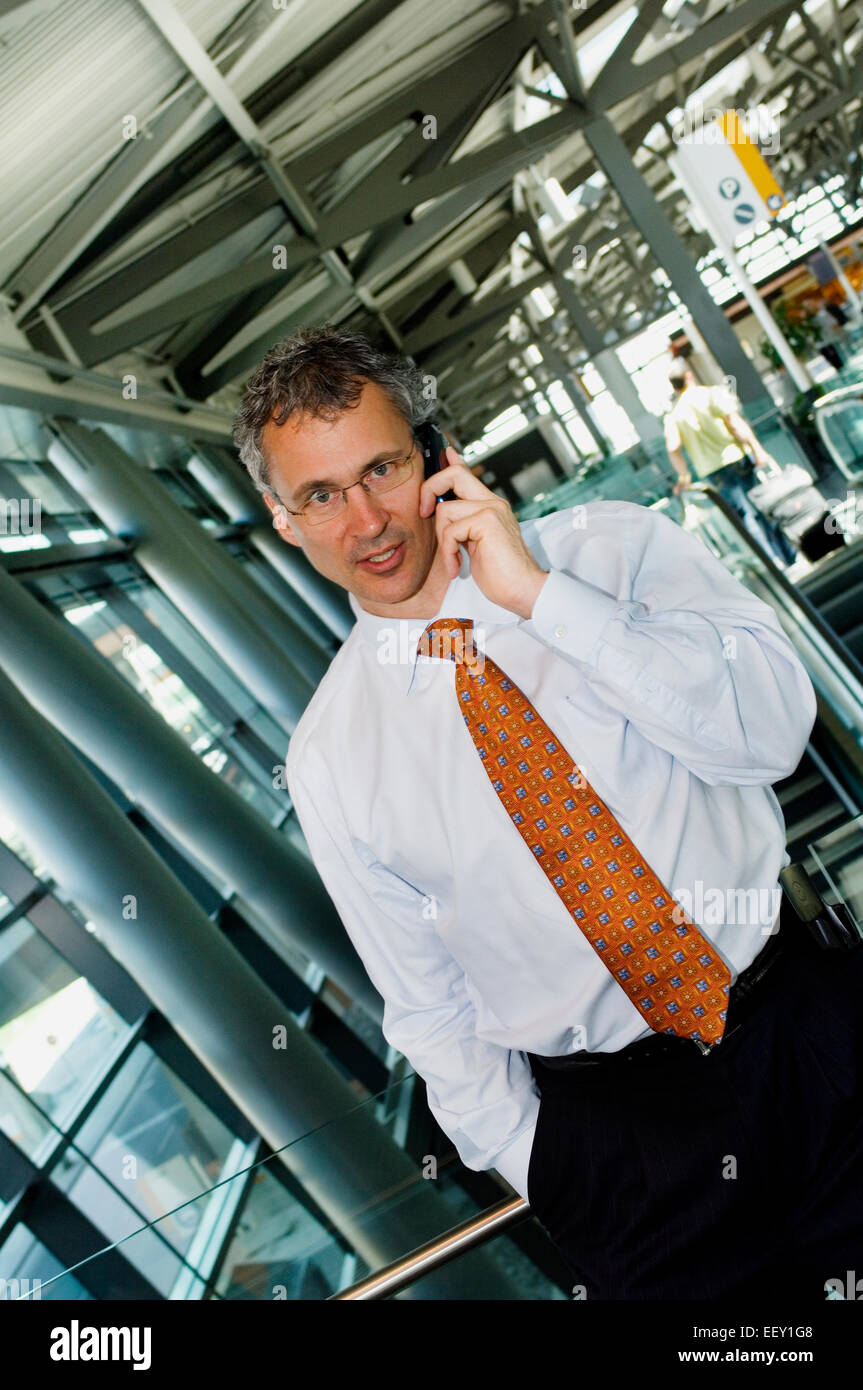 Businessman in airport using personal digital assistant Stock Photo