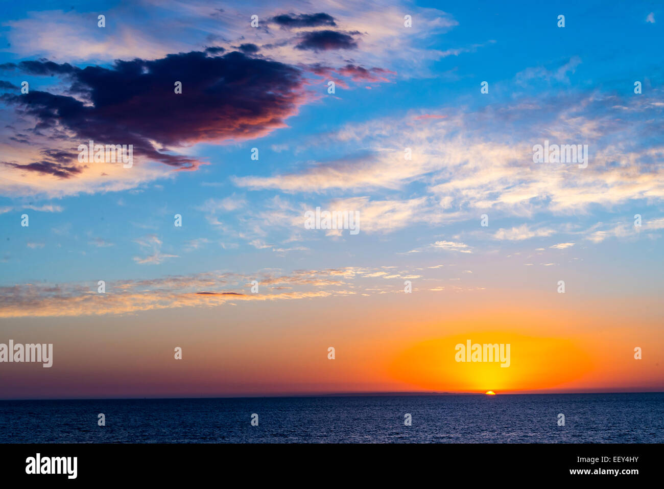 Sunset over sea ocean bright orange blue sky moody dusk Stock Photo - Alamy
