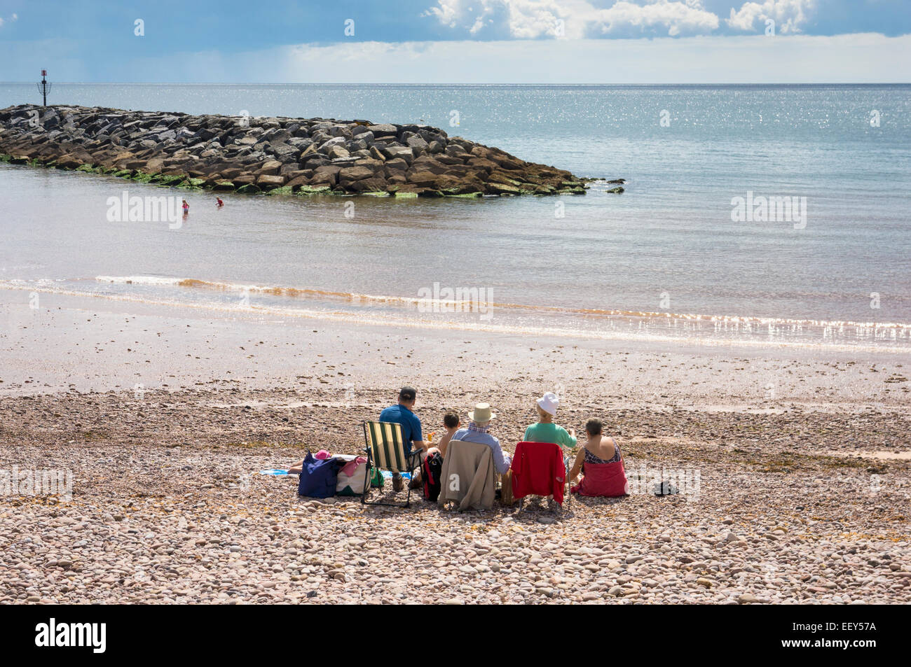 People in deckchairs on the beach on holiday at the seaside uk resort of Sidmouth, East Devon, England, UK Stock Photo