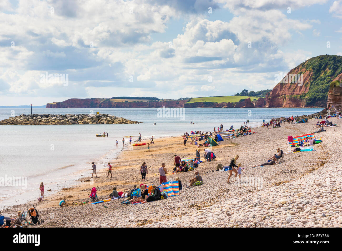 Devon coast - People and families sunbathing on the beach in summer and swimming on the Jurassic Coast, Devon, UK Stock Photo